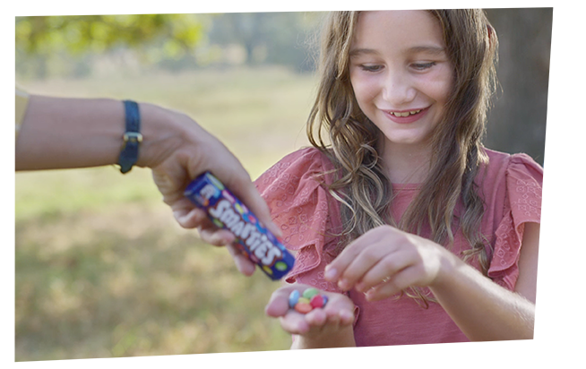 person pouring Smarties sweets into a girl’s hand
